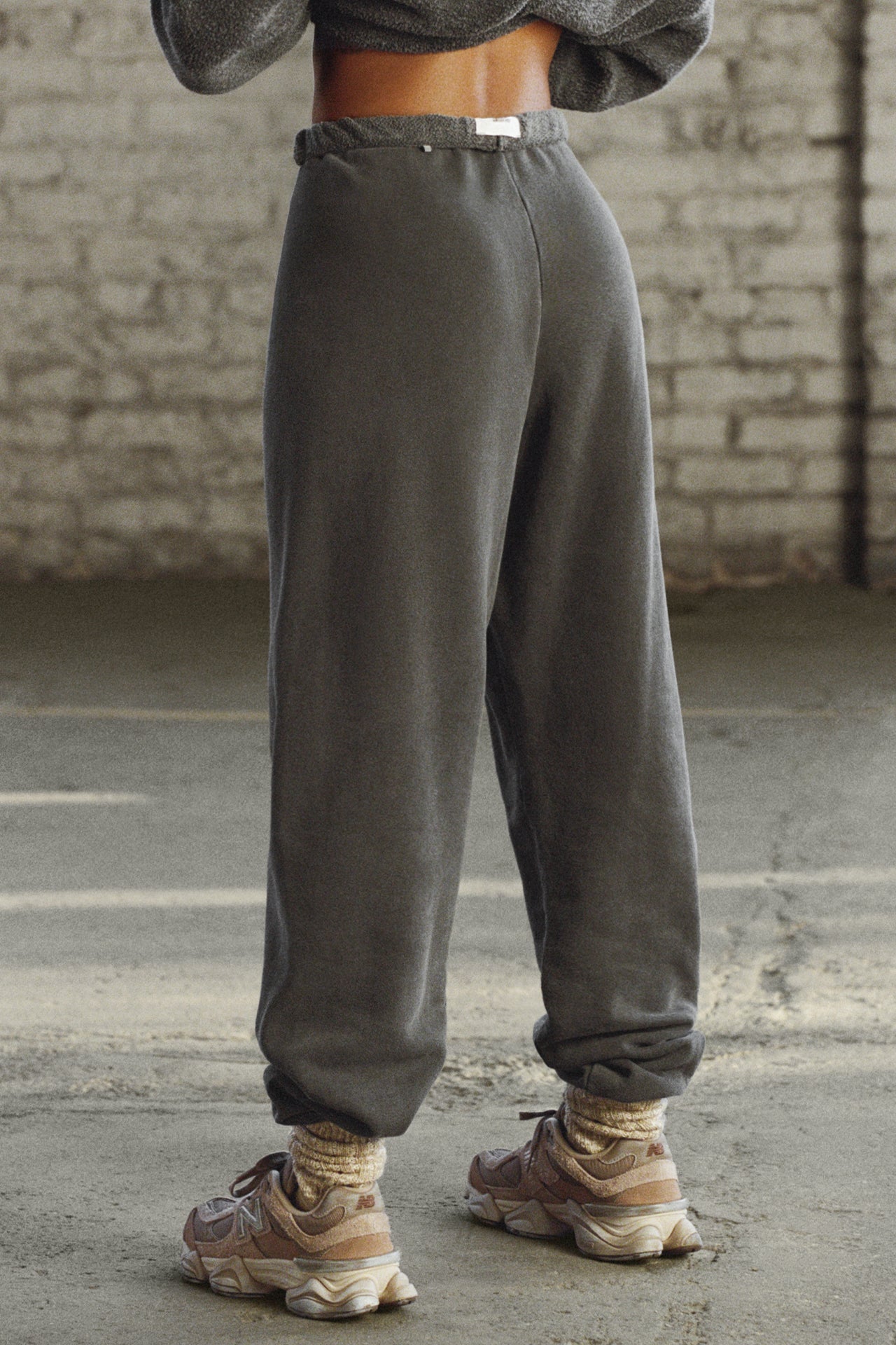 Back view of model from the waist down posing in the oversized loose fit washed black french terry Oversized Jogger with an elastic waistband and ankle cuffs