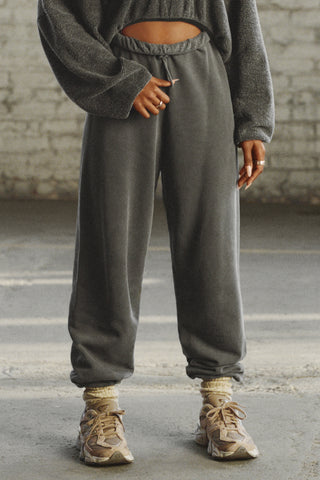 Front view of model from the waist down posing in the oversized loose fit washed black french terry Oversized Jogger with an elastic waistband and ankle cuffs