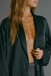Close up front view of model posing in the comfortable, relaxed fit midnight Oversized Silk Button Down Long Sleeve top with a low shawl collar, front button closures and a left chest pocket