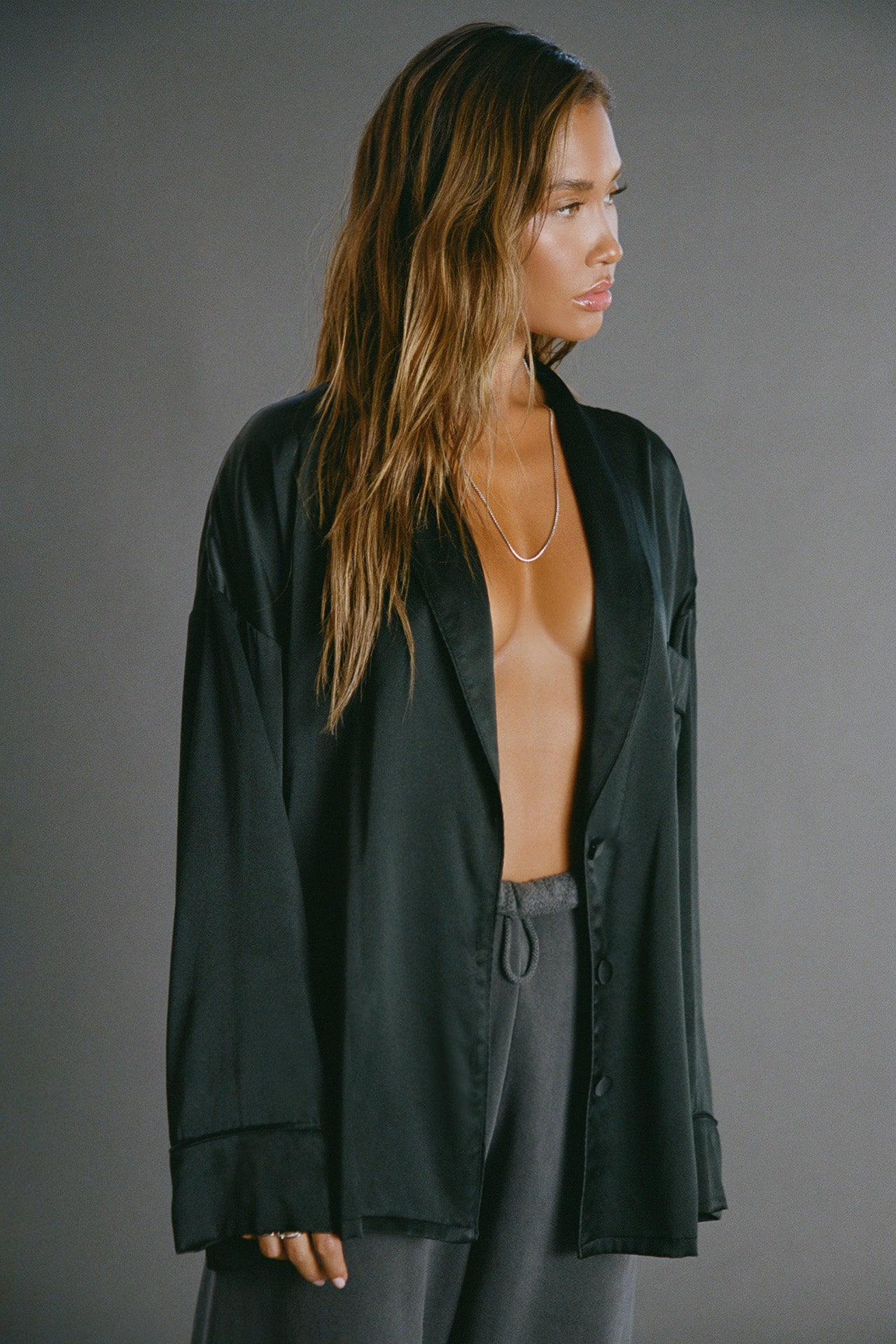 Front view of model posing in the comfortable, relaxed fit midnight Oversized Silk Button Down Long Sleeve top with a low shawl collar, front button closures and a left chest pocket