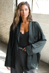 Front view of model posing in the comfortable, relaxed fit midnight Oversized Silk Button Down Long Sleeve top with a low shawl collar, front button closures and a left chest pocket