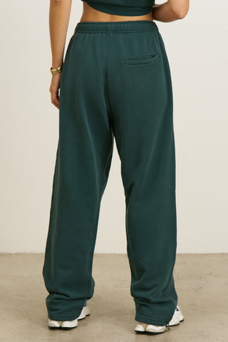 Back view of model from the waist down posing in the relaxed fit alpine french terry Oversized Straight Leg Jogger with an elastic waistband, hidden drawstring, pocket details. and adjustable cinching at the ankle cuffs