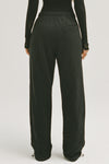 Front view of model from the waist down posing in the relaxed fit black french terry Oversized Straight Leg Jogger with an elastic waistband, hidden drawstring, pocket details. and adjustable cinching at the ankle cuffs