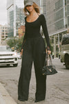 Full body front of model posing outside in the street in the relaxed fit black french terry Oversized Straight Leg Jogger with an elastic waistband, hidden drawstring, pocket details. and adjustable cinching at the ankle cuffs