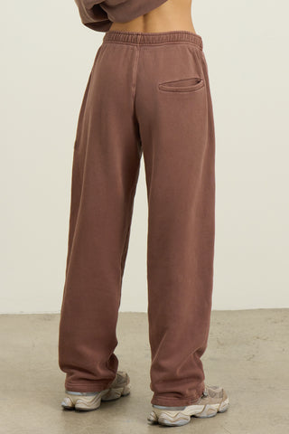 Back view of model from the waist down posing in the relaxed fit cedar french terry Oversized Straight Leg Jogger with an elastic waistband, hidden drawstring, pocket details. and adjustable cinching at the ankle cuffs