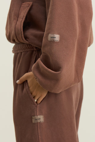 Close up detail side view of model from the waist down posing in the relaxed fit cedar french terry Oversized Straight Leg Jogger with an elastic waistband, hidden drawstring, pocket details. and adjustable cinching at the ankle cuffs