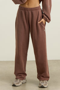 Front view of model from the waist down posing in the relaxed fit cedar french terry Oversized Straight Leg Jogger with an elastic waistband, hidden drawstring, pocket details. and adjustable cinching at the ankle cuffs