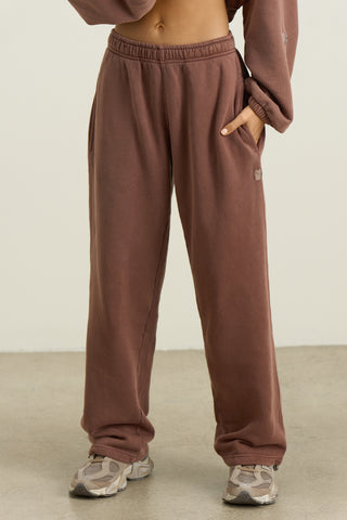 Front view of model from the waist down posing in the relaxed fit cedar french terry Oversized Straight Leg Jogger with an elastic waistband, hidden drawstring, pocket details. and adjustable cinching at the ankle cuffs