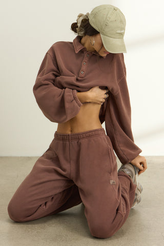 Front view of model posing in the relaxed fit black french terry Oversized Straight Leg Jogger with an elastic waistband, hidden drawstring, pocket details. and adjustable cinching at the ankle cuffs