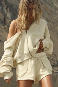 Front view of model posing outside in the relaxed fit buttercream french terry Classic Zip Hoodie with a full length front zip closure, side pockets and thumbholes in the fitted cuffs