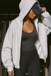 Front view of model posing in the oversized comfortable pearl grey french terry Oversized Zip Hoodie with a full length front zip closure, side pockets and thumbholes in the fitted cuffs
