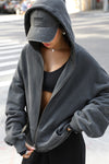 Front view of model posing in the oversized comfortable washed black french terry Oversized Zip Hoodie with a full length front zip closure, side pockets and thumbholes in the fitted cuffs