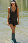 Full body front view of model posing outside by a lake in the lightweight relaxed fit black modal Plunge Tank with a plunging u-neckline