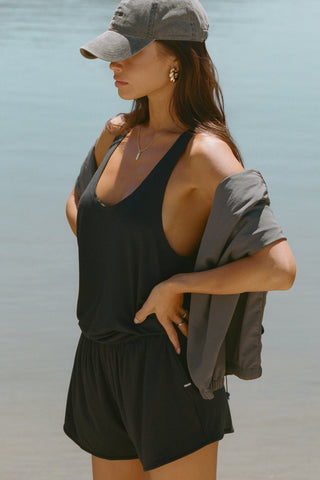 Side view of model posing outside by a lake in the lightweight relaxed fit black modal Plunge Tank with a plunging u-neckline