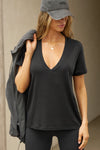 Front view of model posing in the full length relaxed fit  black modal Plunge V Neck Tee with an plunging v-neckline