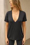 Front view of model posing in the full length relaxed fit  black modal Plunge V Neck Tee with an plunging v-neckline