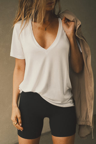 Front view of model posing in the full length relaxed fit white modal Plunge V Neck Tee with an plunging v-neckline