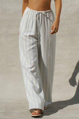 Front view of model from the waist down posing in the relaxed fit lightweight natural white and blue stripe gauze Relaxed Everyday Pant with an elastic waistband and adjustable front tie