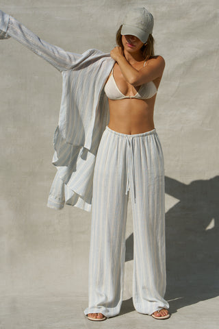 Full body front view of model posing in the relaxed fit lightweight natural white and blue stripe gauze Relaxed Everyday Pant with an elastic waistband and adjustable front tie