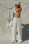 Full body front view of model posing in the relaxed fit lightweight natural white and blue stripe gauze Relaxed Everyday Pant with an elastic waistband and adjustable front tie