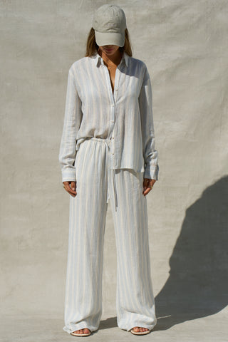 Full body front view of model posing in the relaxed fit lightweight natural white and blue stripe gauze Relaxed Everyday Pant with an elastic waistband and adjustable front tie