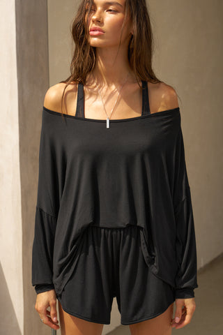 Front view of model posing in the full-length black modal Relaxed Long Sleeve top with dropped shoulders and a wide neckline that can be worn off the shoulders.