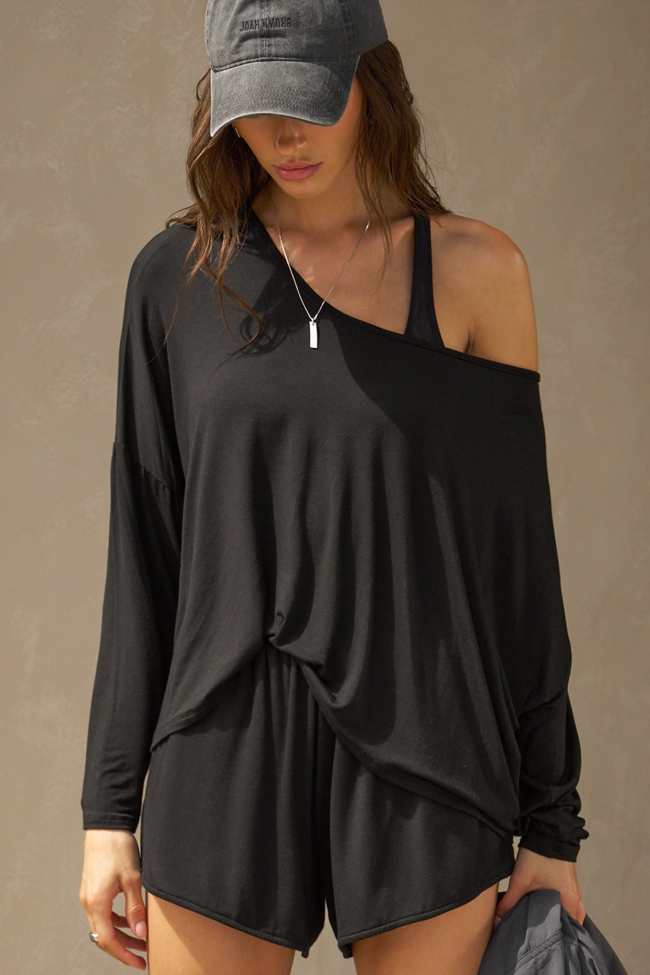 Front view of model posing in the full-length black modal Relaxed Long Sleeve top with dropped shoulders and a wide neckline that can be worn off the shoulders.