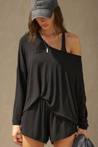 Front view of model posing in the full-length black modal Relaxed Long Sleeve top with dropped shoulders and a wide neckline that can be worn off the shoulders.