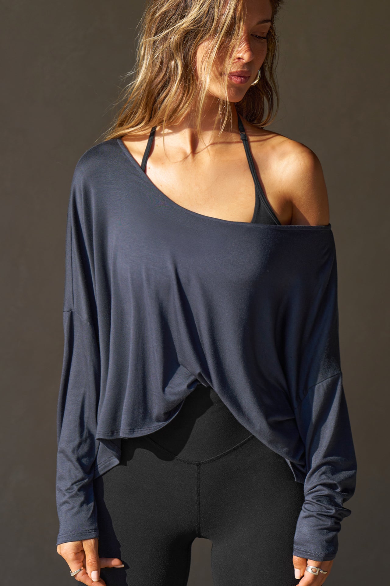 Front view of model posing in the full-length navy modal Relaxed Long Sleeve top with dropped shoulders and a wide neckline that can be worn off the shoulders.