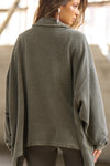 Back view of model posing in the loose-fitting oakmoss sherpa Relaxed Shirt Jacket with a classic collar, front button closures, side pockets, and a curved hem.