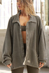 Front view of model posing in the loose-fitting oakmoss sherpa Relaxed Shirt Jacket with a classic collar, front button closures, side pockets, and a curved hem.