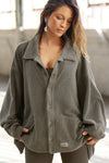 Front view of model posing in the loose-fitting oakmoss sherpa Relaxed Shirt Jacket with a classic collar, front button closures, side pockets, and a curved hem.