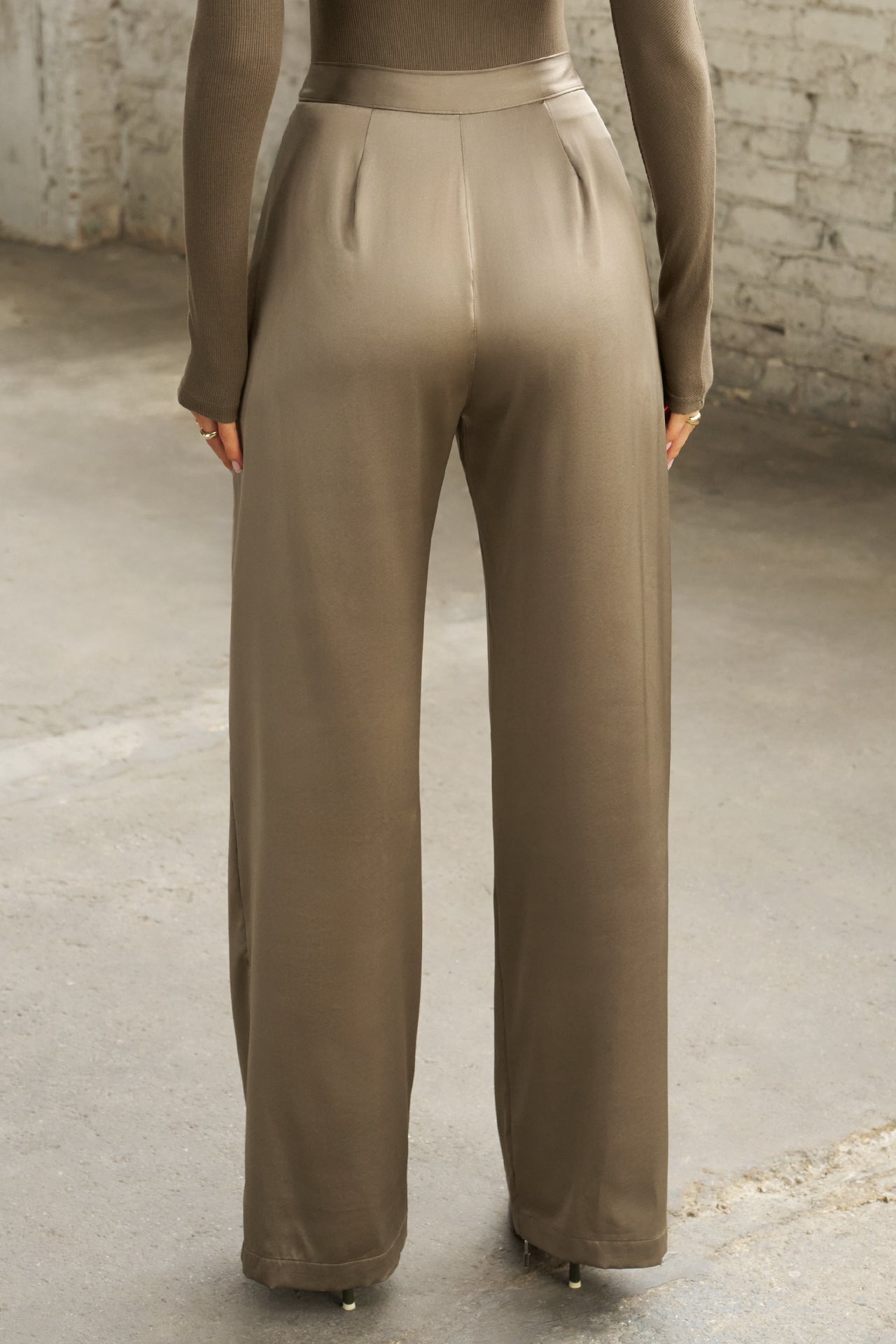 Back view of model from the waist down posing in the soft and smooth classic pleated saebrush  Relaxed Silk Trouser with a flattering wide leg, zip fly and side pockets.