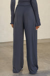 Back view of model from the waist down posing in the relaxed fit navy modal Relaxed Straight Leg Pant with a wide leg, elastic waistband, adjustable drawstring tie and subtle pleating at the sides.