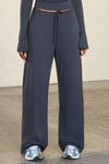 Front view of model from the waist down posing in the relaxed fit navy modal Relaxed Straight Leg Pant with a wide leg, elastic waistband, adjustable drawstring tie and subtle pleating at the sides.