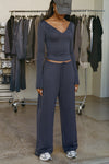 Full body front view of model posing in the relaxed fit navy modal Relaxed Straight Leg Pant with a wide leg, elastic waistband, adjustable drawstring tie and subtle pleating at the sides.
