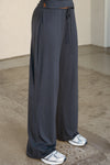 Side view of model from the waist down posing in the relaxed fit navy modal Relaxed Straight Leg Pant with a wide leg, elastic waistband, adjustable drawstring tie and subtle pleating at the sides.