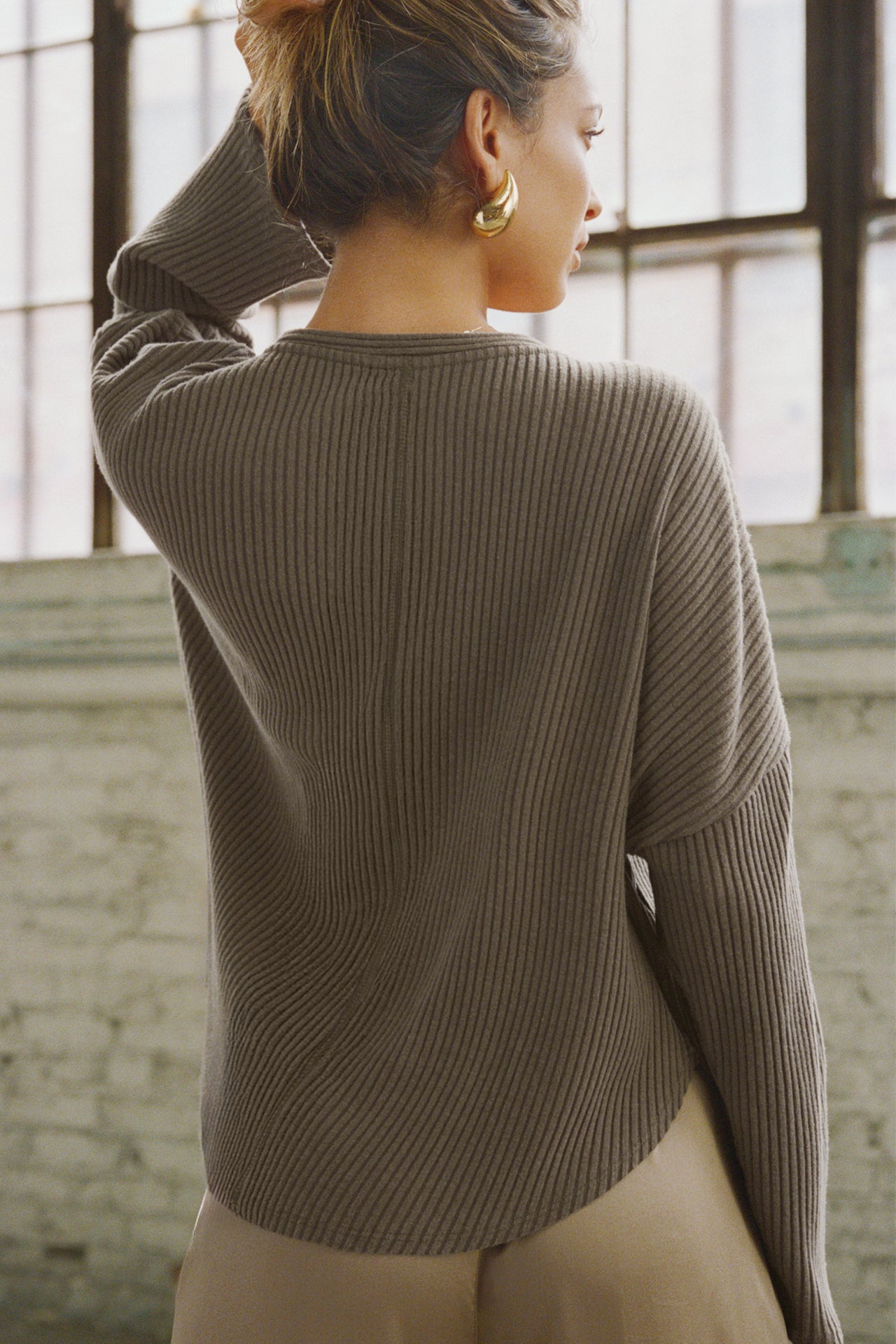 Back view of model posing in the relaxed-fit, long sleeve army luxe knit Relaxed V-Neck Cardigan with front button closures and a V-neckline.