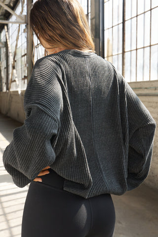Back view of model posing in the relaxed-fit, long sleeve ink luxe knit Relaxed V-Neck Cardigan with front button closures and a V-neckline.
