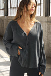 Front view of model posing in the relaxed-fit, long sleeve ink luxe knit Relaxed V-Neck Cardigan with front button closures and a V-neckline.