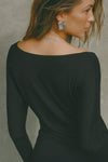 Close up back view of model posing in soft and lightweight black modal Ruched Asymmetrical Long Sleeve top with fitted sleeves, a relaxed asymmetrical hemline and a flattering ruched side detail