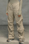 Front view of model from the waist down posing in the relaxed fit, desert sage nylon Ruched Track Pant with a wide leg, side ruched panels and finished with a drawcord waist, side pockets and adjustable button closures at the ankle.