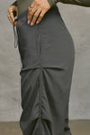 Close up side view of model from the waist down posing in the relaxed fit, jet nylon Ruched Track Pant with a wide leg, side ruched panels and finished with a drawcord waist, side pockets and adjustable button closures at the ankle.