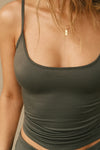 Close up detail front view of model posing in the fitted spruce modal Scoop Neck Cami with thin adjustable straps, scoop neckline and scoop back