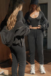 Full body front view of model posing in front of a mirror in the fitted lightweight black modal Scoop Neck Long Sleeve top with a deep scoop neckline and fitted sleeves