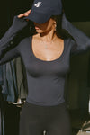 Front view of model posing the fitted lightweight navy modal Scoop Neck Long Sleeve top with a deep scoop neckline and fitted sleeves