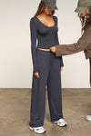 Full body side view of model posing the fitted lightweight navy modal Scoop Neck Long Sleeve top with a deep scoop neckline and fitted sleeves