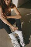 Front view of model adjusting the slouchy classic white Scrunch Sock with extra long ribbed cuffs