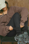 Front view of model adjusting the slouchy coal Scrunch Sock with extra long ribbed cuffs
