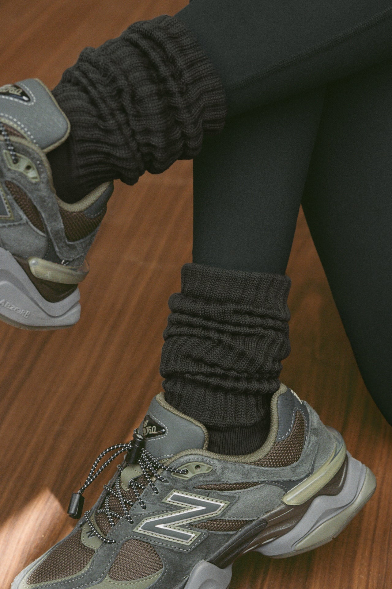 Close up detail side view of model posing in the slouchy coal Scrunch Sock with extra long ribbed cuffs